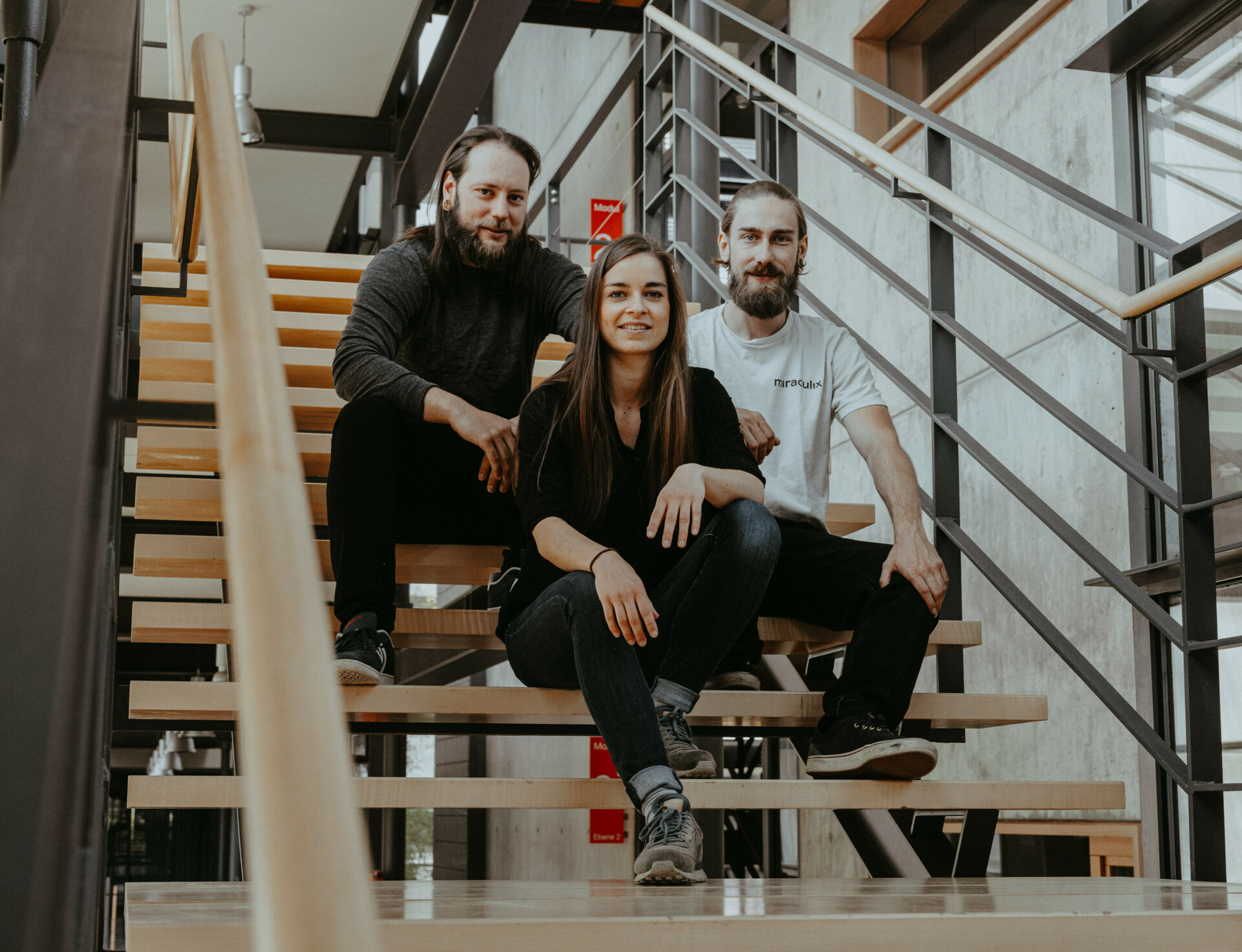 miraculix Team Dr. Felix Blei, Roxana Preuß und Frank Junger sitzen auf als Team auf einer Treppe